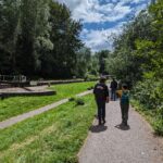 team members walking along tow path of canal with lock in back ground