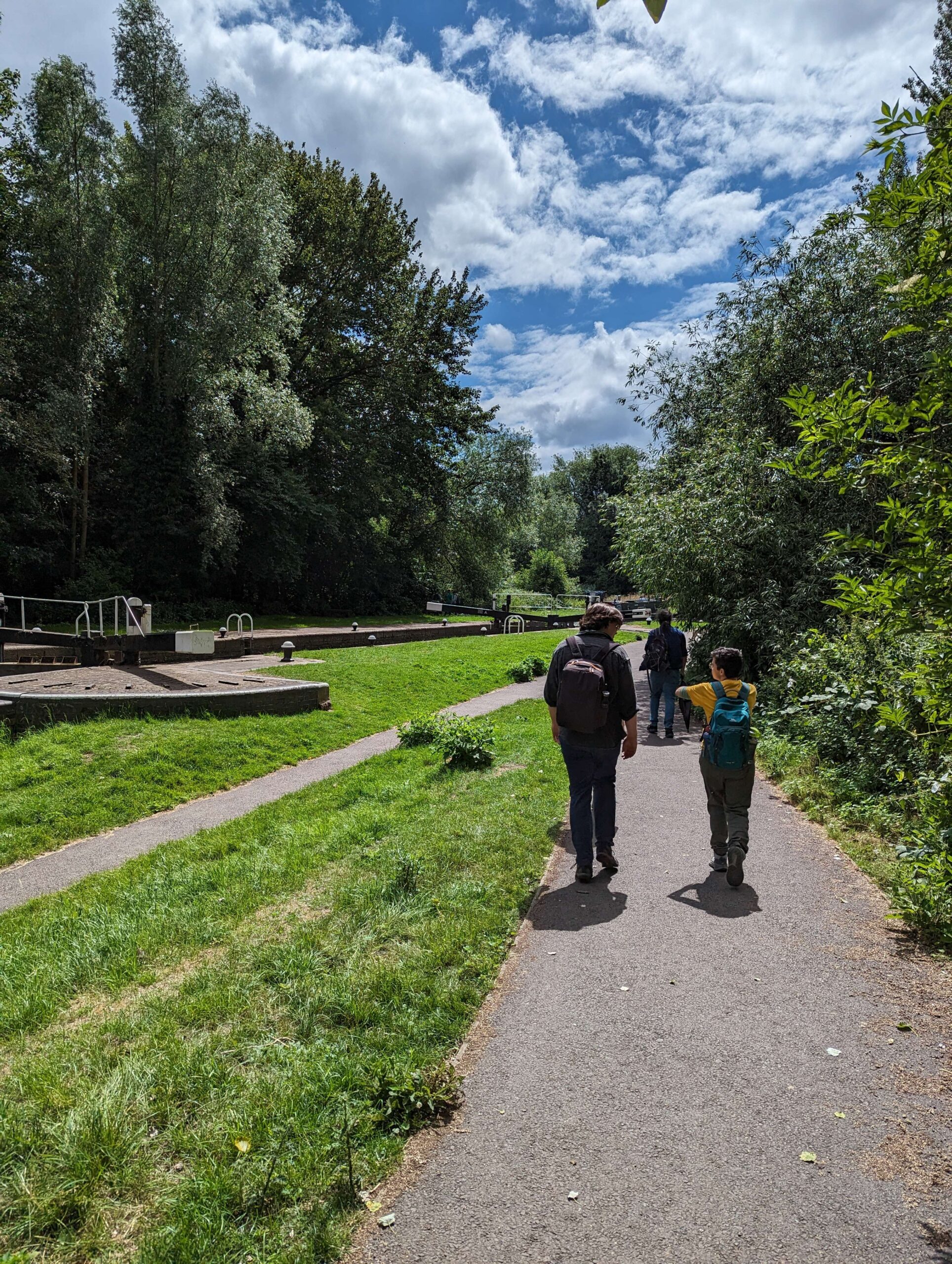 team members walking along tow path of canal with lock in back ground